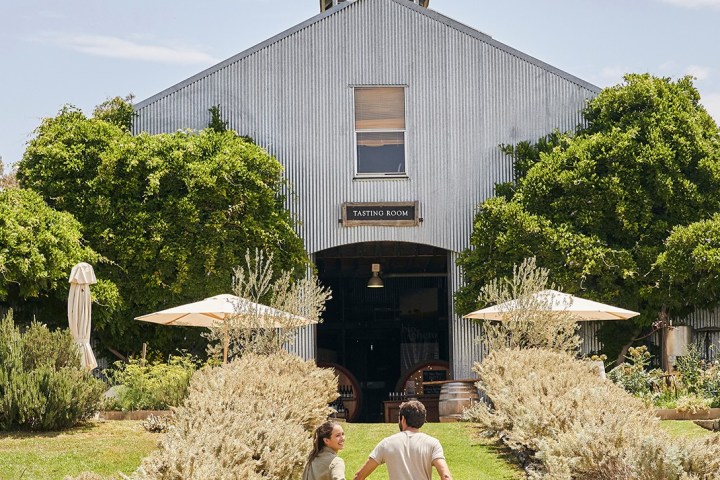 a person that is standing in the grass near a building
